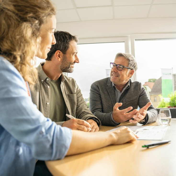Two farmers sit at a table with a Fendt dealer and get advice.